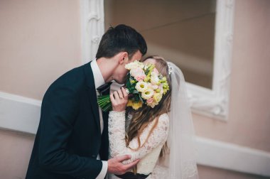 Bir buket çiçekli zarif bir gelin aynanın yanında duruyor. Öptüm. Buket yüzünü kapattı, yeni evlileri sakladı. Sarılalım. Kapatın. Portre. Geçmişe dönüş. Klasik mimari içeride..