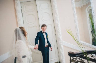 Damatla dans eden zarif bir gelin merdivenlerde duruyor ve kapıların yanında parmaklıklar var. Kapatın. Portre. Geçmişe dönüş. Kapalı alanda klasik mimari. Sahte metal merdiven.