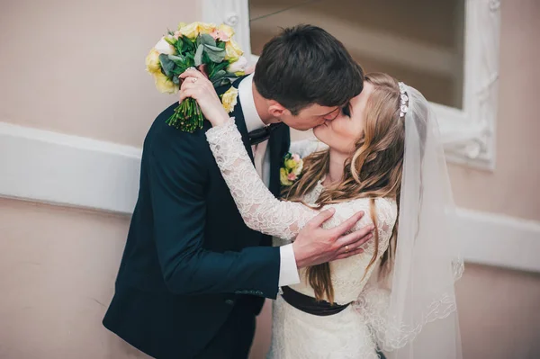 꽃다발을 아름답고 신부가 근처의 계단에 근처에 입술로 신랑에게 키스하는 초상화 — 스톡 사진