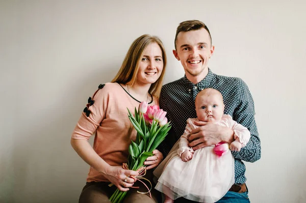 여자가 소녀를 아버지는 배경에 분홍빛 꽃다발을 놓는다 여성의 어머니 — 스톡 사진