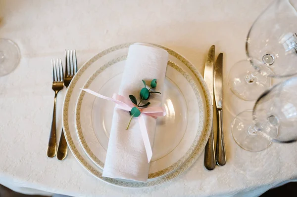 Serving, setting table. Two plates and silverware cutlery  linen napkin are decorated with pink ribbons and branch greens. Wedding table decoration. Artwork. flat lay. top view.