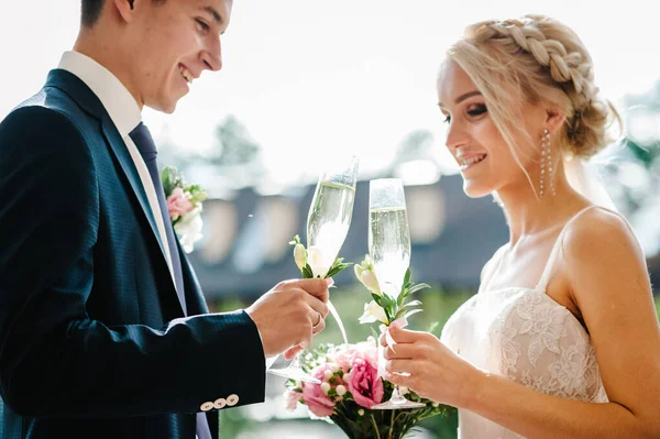 新婚夫妇举着香槟酒在户外祝酒 站在后院落宴会厅的拱门下举行婚礼 装饰着鲜花和绿叶 — 图库照片