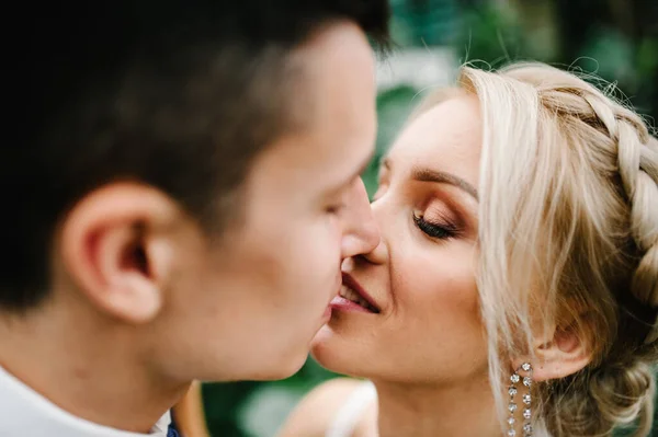 新郎と新婦の緑の背景にキスを肖像画 植物園での結婚式 — ストック写真