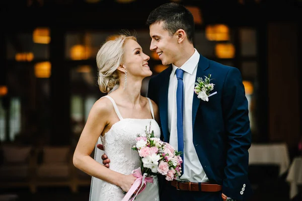 結婚式では ロマンチックなカップルの新婚旅行 新郎新婦がピンクと紫の花と緑のリボンの花束を持っています 幸せと喜びの結婚式の瞬間 — ストック写真