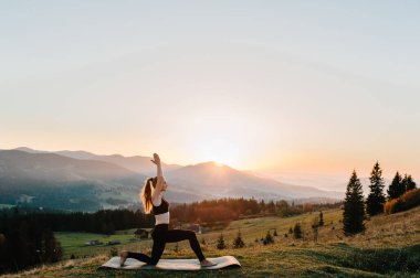 Genç bir kadın Namaste Asana ile kompleks Hatha Yoga egzersizi yapıyor. İnanılmaz bir yoga tahtası güzel dağlarda açık havada poz veriyor..