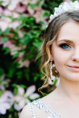 Yarım yüz, taç takmış mutlu bir kadının portresi. Kameraya bakarak gülümsüyor. Çekici, kendinden emin, ciddi ve yakışıklı. Genç gelin arka planda yalnız..