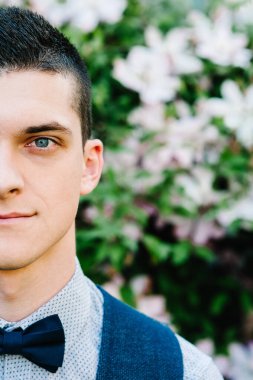 Yarım yüz, insan portresi. Kameraya bakarak gülümsüyor. Çekici, kendinden emin, ciddi ve yakışıklı. Arka planda yaşayan genç bir insan. Takım elbiseli bir kelebek..