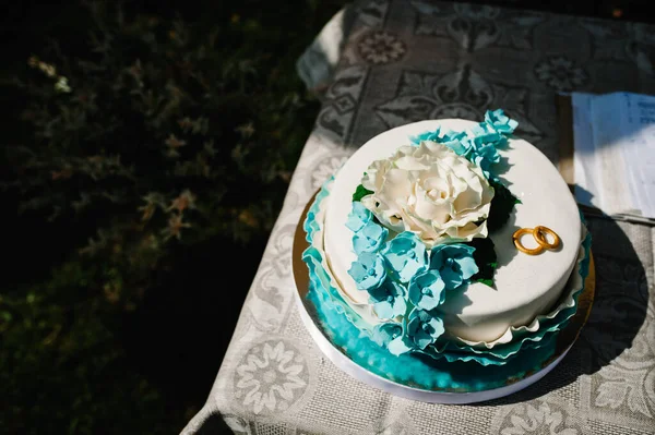 結婚式のケーキは 結婚式の雑誌の近くのテーブルで 結婚式のパンの背景に2つの黄金の結婚指輪 いいテーブルだ デザートだ 甘みだ 優しい音色だ 閉じろ — ストック写真