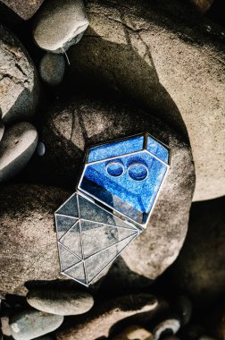 Altın alyanslar cam şeklindeki metal bir kutuda elmas şeklinde duruyor. Yuvarlak büyük taşların arkasında. Parlak mavi bir yüzükte evlilik yüzüğü. Kapat.