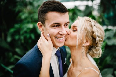 Yeni evliler yeşillik dolu Botanik bahçesinde durup öpüşüyorlar. Düğün töreni..