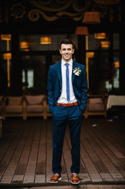 Zengin, çekici, neşeli damat özel bölgede evin yanında duruyor. Açık havada..