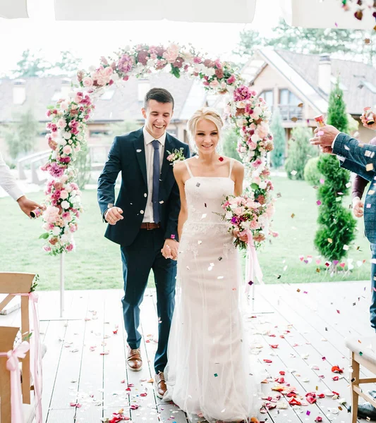 Recém Casados Atravessam Arco Com Folhas Rosas Confetes Coloridos Cerimônia — Fotografia de Stock