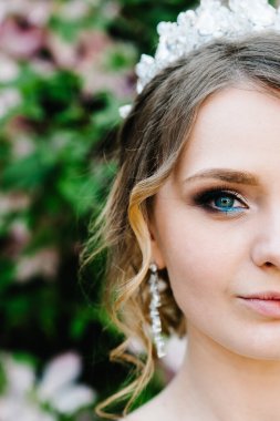 Yarım yüz, taç takmış mutlu bir kadının portresi. Kameraya bakıyorum. Çekici, kendinden emin, ciddi ve yakışıklı. Genç gelin arka planda yalnız..