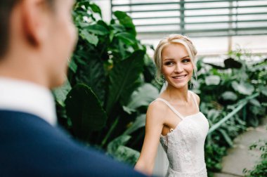 Gelin yeşillik dolu Botanik Bahçesi 'nde damada bakıyor. Düğün töreni. Yeni evliler.