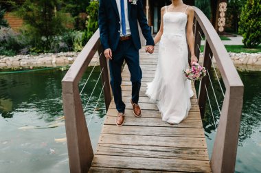 En alttaki çiftin görüntüsü. Yeni evliler. Gelin ve damat bir göl ya da nehir kıyısında yürüyorlar..