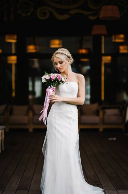 Düğün buketi olan gelin ziyafet alanındaki düğün töreninde ayakta duruyor..