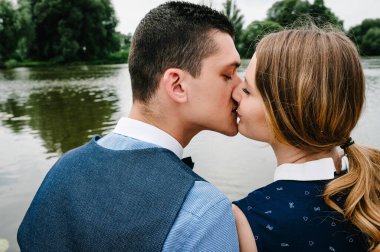 Genç insanların yüzü. Ayakta duran, sarılan, arka planda öpüşen bir çift. Kapatın. Vesikalık, yarım boy. Bir kadın, gözlerini kapatan bir adam..