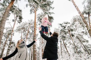 Anne, baba oyun oynuyor ve kızını kış parkına kusuyor. Dışarıda mutlu bir aile portresi, parkta yürüyüş. Aile tatili kavramı. Kapatın. Mutluluk duyguları. Bebek..
