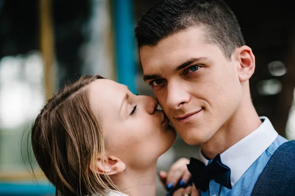 The face of young people. A young couple standing, hugging and kissing near a wooden old house on the background with beams and windows. Close up. headshot, half length.