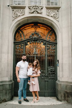 Genç, mutlu bir aile: Baba, anne ve kız eski şehrin, kasabanın, açık havanın antik mimarisinin yakınındaki bir sokakta yürürken. Aile tatili ve seyahat kavramı.