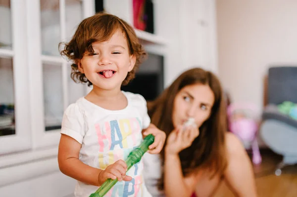 Mom and daughter hold toys, playing in game in the room indoor in home. Happy family portrait: mother and girl, concept of a family holiday. Close up. Emotions of happiness.