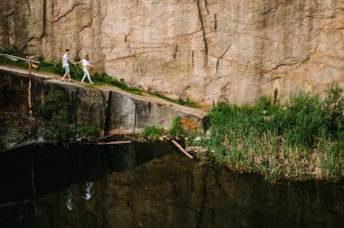 Kayaların arka planında göle yaklaşan insanların yansıması. Suyla dolu eski bir endüstriyel granit ocağının manzarası. Kanyon. Sonbaharın doğası. Metin ve tasarım için yer.