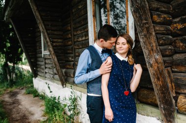 Genç aşıklar eski ahşap bir evin yanında duruyorlar. Bir erkek şefkatli bir kadına sarılır. Üst yarısı. Aşağıya bakıyor. huş ağacının ve doğanın arka planında.