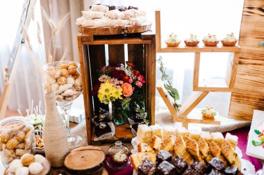 Düğün çikolatası. Ahşap ve kır çiçeklerinden yapılmış dekorasyonlar düğün töreni için şenlik masasında sergileniyor. Ahşap sahne, restoran duvarları parti için..