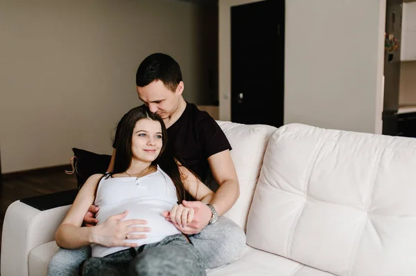 Image of husband holding belly of his pregnant wife hands. Pregnant woman and loving handsome man hugging tummy at home. Loving Couple. Parenthood concept. Baby Shower.