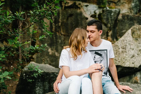 Young Man Hugs Kisses Girl Young Couple Sitting Big Stone — Stock Photo, Image