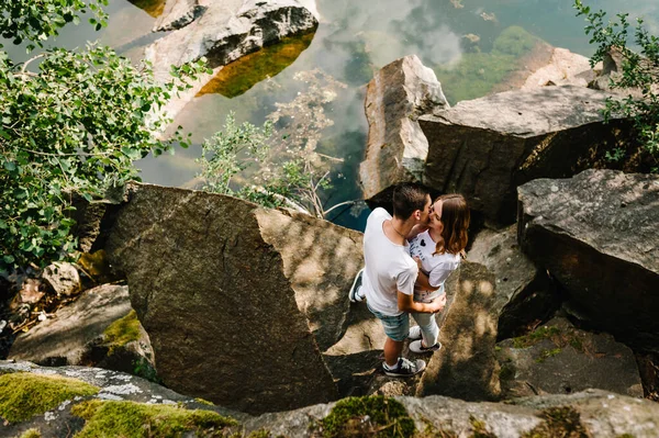 若いカップル抱擁し 湖の近くの石にキス 岩を背景に男と女が立っている 最上階だ お互いを見ていると — ストック写真