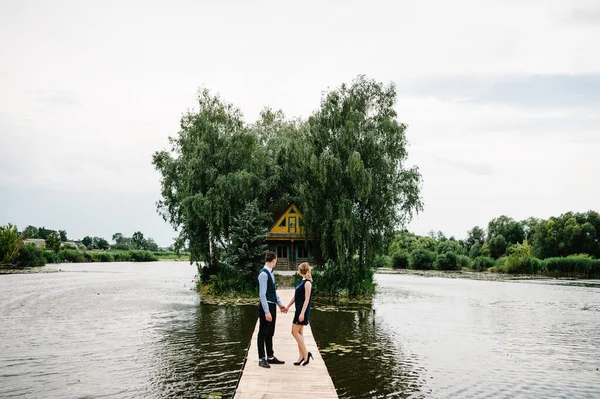 Mladý Pár Drží Ruce Jde Dřevěném Mostě Nad Jezerem Pozadí — Stock fotografie