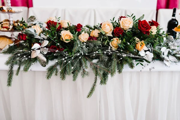 Winter Wedding decor. Winter green garland. Table decorations. White candles and flowers. Setting at winter wedding reception, floral composition.