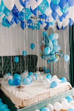 Geniş ve açık renkli, beyaz ve mavi balonlu bir yatak odası. Bebek partisi için güzel dekorasyonlar..