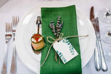 Misafirleri ağırlamak, masayı hazırlamak. İki tabak, çatal bıçak takımı, lavantalı yeşil keten peçete. Düğün masası dekorasyonu. Düz yat. Üst Manzara. Kapat..