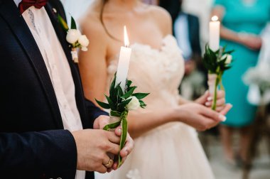 Gelin ve damat el ele tutuşuyor. Mumu yak. Hristiyan kilisesinde düğün töreninde ellerinde mum tutan ruhani bir çift. Kapat..
