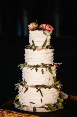 Düğün yemeği için pembe çiçekli beyaz düğün pastası. Nefis bir düğün resepsiyonu. Uzayı kopyala Kutlama partisi konsepti. Moda Pastası.