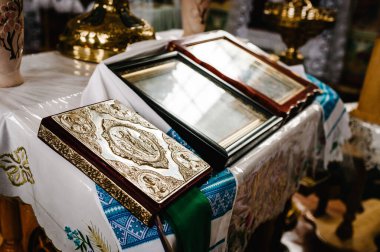 Kilisedeki masanın üzerinde altın ve simgelerle süslenmiş kutsal İncil var. Kapat..