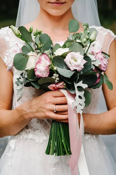 穿着雅致衣服的年轻漂亮的姑娘正站在那里 手里拿着一束束带彩带的淡淡的鲜花和绿叶 新娘在户外举行婚礼 — 图库照片