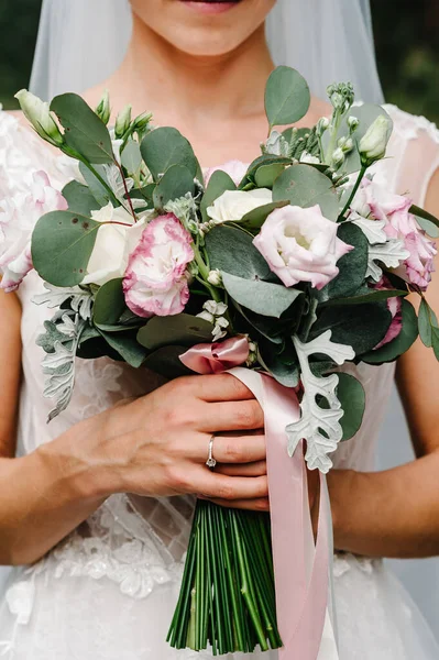 エレガントなドレスの若い美しい女の子が立っており 自然のリボンとパステルの花や緑の手花束を保持しています 花嫁は屋外で結婚式の花束を保持します — ストック写真
