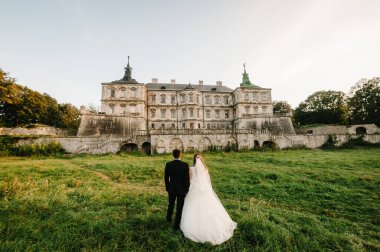 Yeni evliler düğün töreni için Rönesans Sarayı 'ndaki Vintage Castle' a doğru yürüyorlar. Fotoğraf çekimi Ortaçağ Kalesi yakınlarında..
