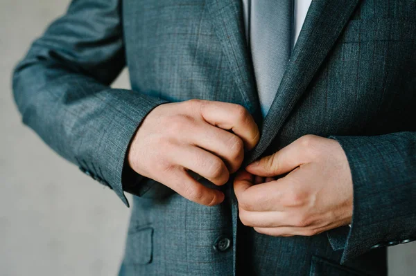 人把扣子系上 穿着西装 领带的新郎站在灰色的背景上 靠近点 — 图库照片