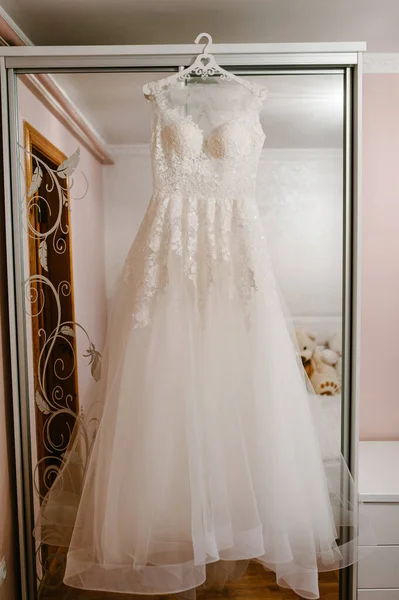部屋のハンガーに掛けられた美しい古典的なウェディングドレス 朝の準備結婚式のコンセプト ヴィンテージウェディングドレス — ストック写真