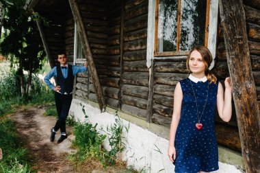 Huş ağacının ve doğanın arka planında eski ahşap bir evin yanında duran genç çift. Bir erkek bir kadından uzaktır. Tam boy. Kameraya yan bakıyorum. Aşk kaybı. Hayal kırıklığı..