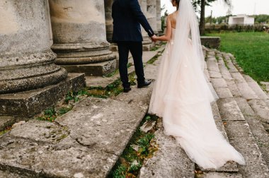 Güzel bir portre. Düğün çifti el ele tutuşuyor. Eski mimari, eski bina, eski saray... Nişan. Atmosfer sokağı. alt, arka plan.