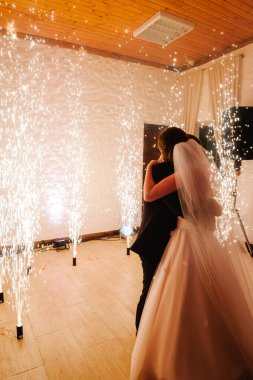 Yeni evlilerin ilk düğün dansı. Muhteşem bir ışık ve atmosferi olan zarif bir restoranda altın havai fişekler altında dans edip öpüşen mutlu gelin ve damat. Romantik anlar. Dans eden çift.