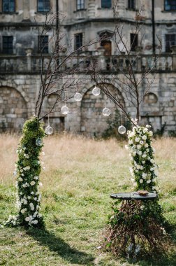 Düğün kemeri A çiçeklerle, yeşilliklerle, yeşilliklerle süslenir. Eski kalenin arka planına karşı. Arka bahçedeki ziyafet alanında düğün dekoru..