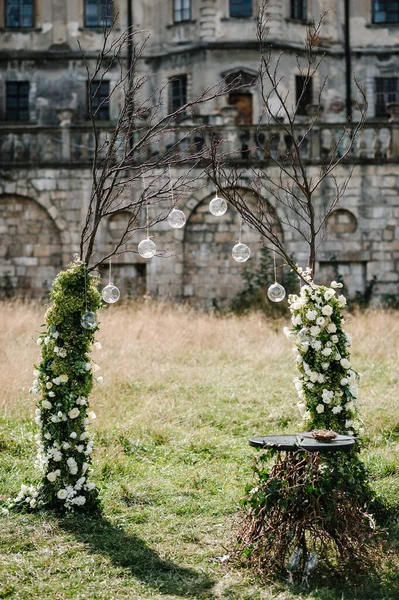 Düğün kemeri A çiçeklerle, yeşilliklerle, yeşilliklerle süslenir. Eski kalenin arka planına karşı. Arka bahçedeki ziyafet alanında düğün dekoru..