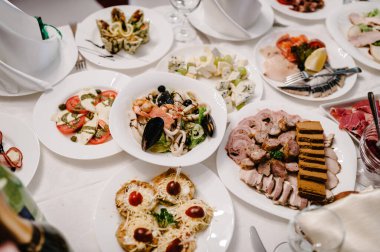 Şenlik masasında yemek servisi yapıyor. Yemek, salata, et, balık menüsü. Düğün ziyafetinde şölen masası. Dekorasyon. Ayrıntılar.