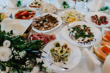 Şenlik masasında yemek servisi yapıyor. Yemek, salata, et, balık menüsü. Düğün ziyafetinde şölen masası. Dekorasyon. Ayrıntılar.
